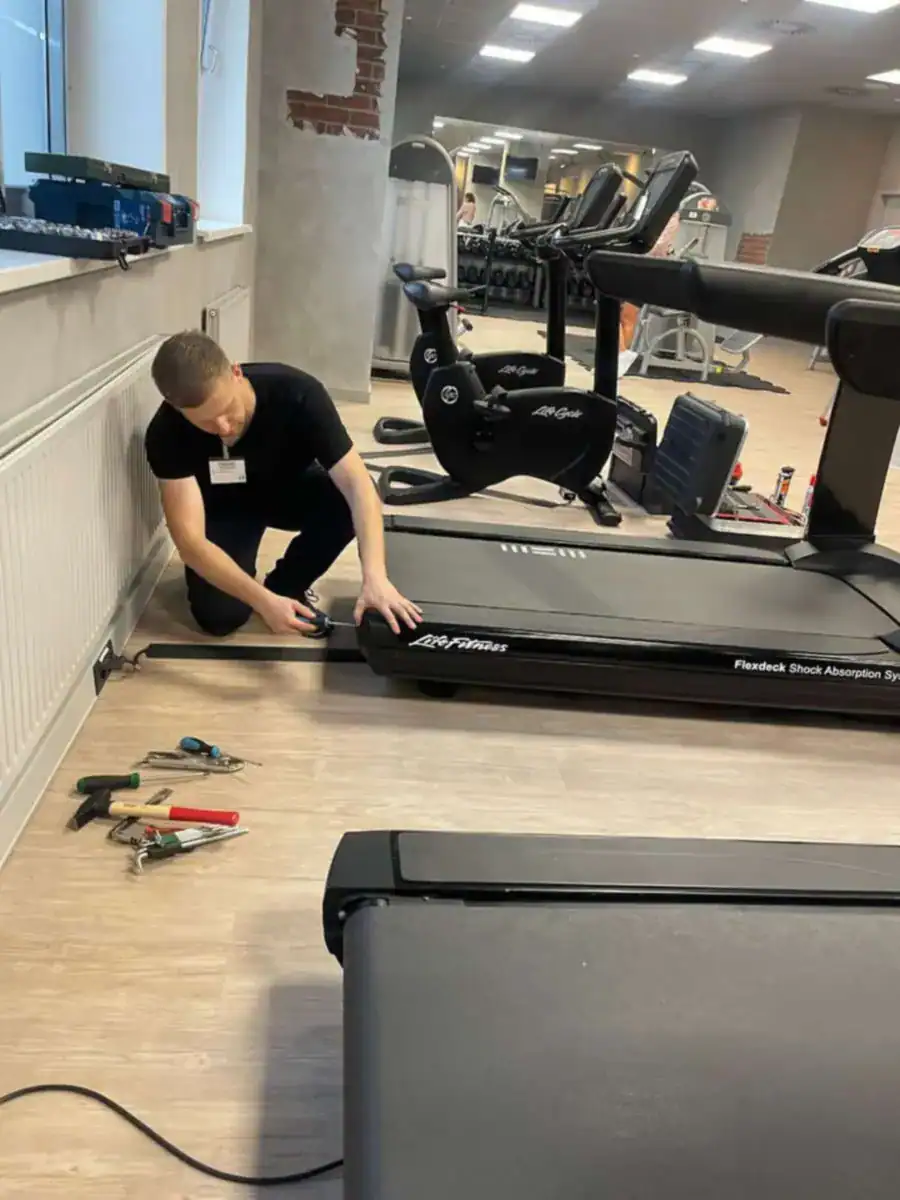 Technicus voert onderhoud en reparatie uit aan een loopband in een fitnessstudio in Nederland