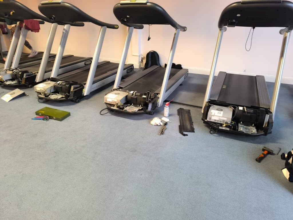 Meerdere Technogym loopbanden met geopende motorruimte tijdens technisch onderhoud en service in een fitnessruimte.